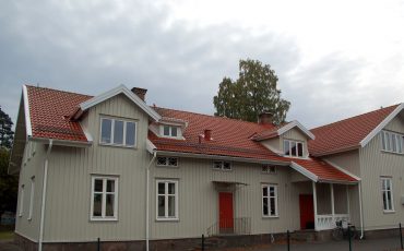 Bild på Nyckelpigans förskola som är beige träbyggnad med vackert rött tegeltak och röda dörrar.