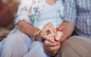 Bild på äldre personer som håller varandra i handen