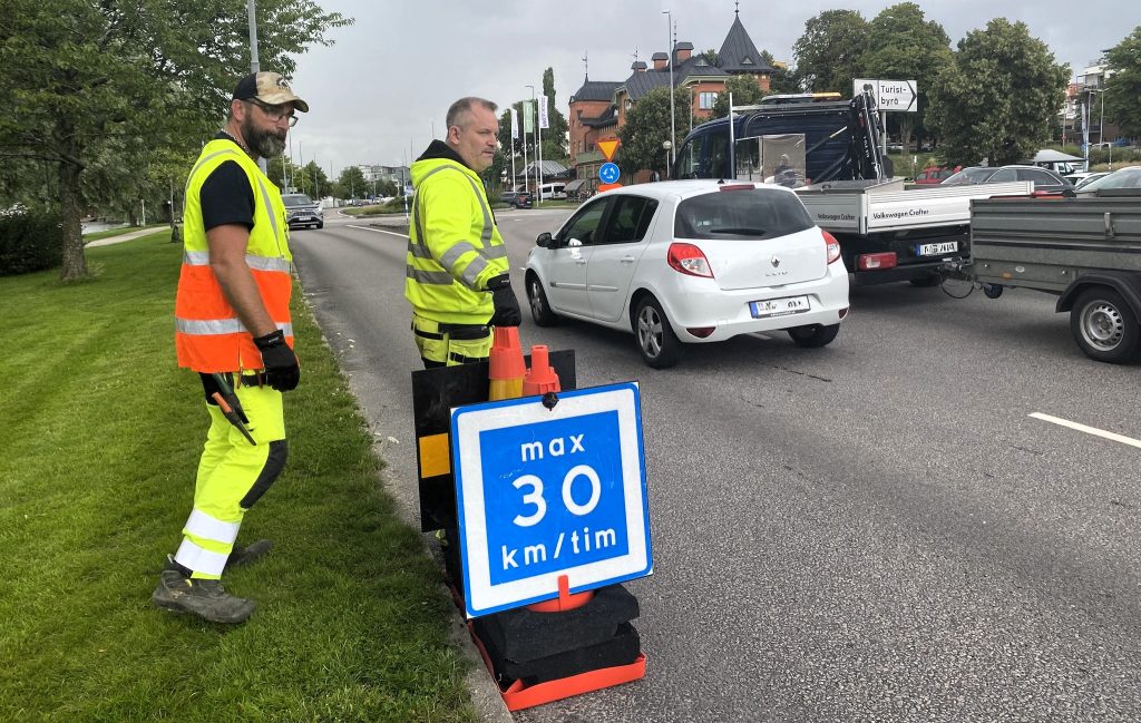 Bilar som kör längs en väg och en hastighetsskylt som visar 30 km/h.