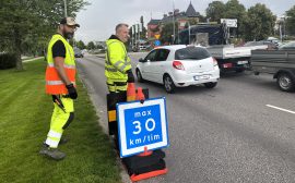 Bilar som kör längs en väg och en hastighetsskylt som visar 30 km/h.